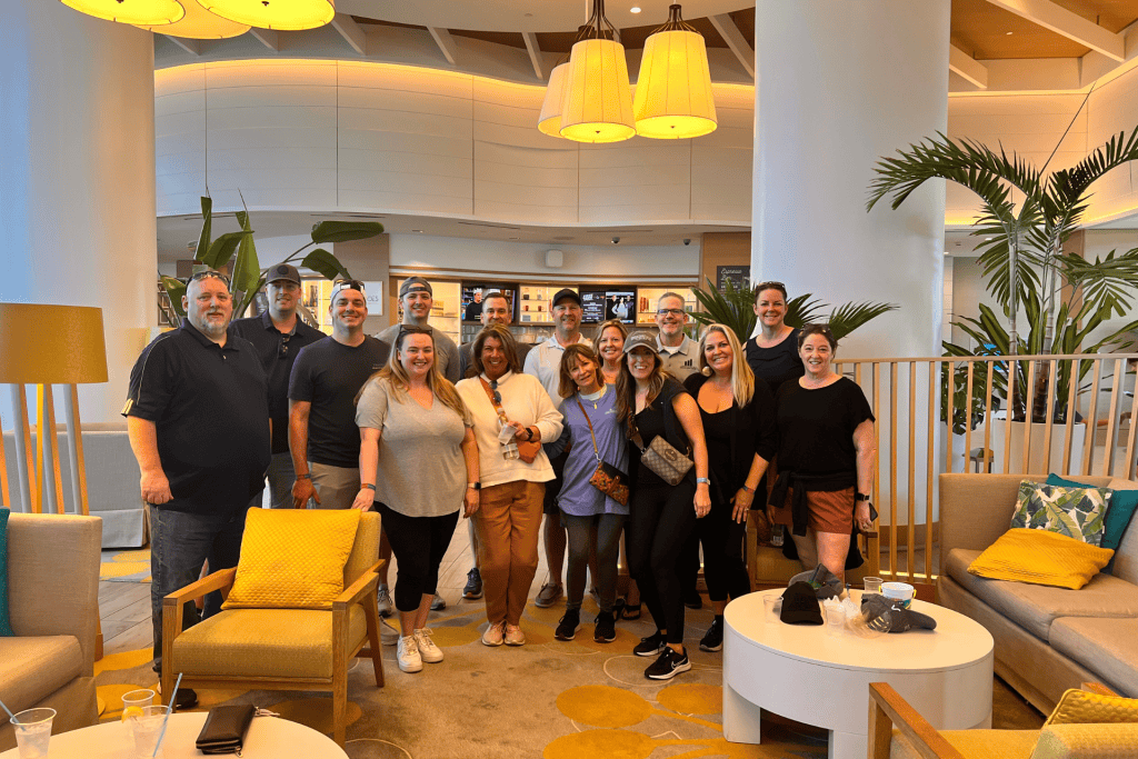 Group of marketing professionals gathered in a modern, well-lit lounge area, showcasing collaboration and networking in a vibrant setting, with plants and comfortable seating.